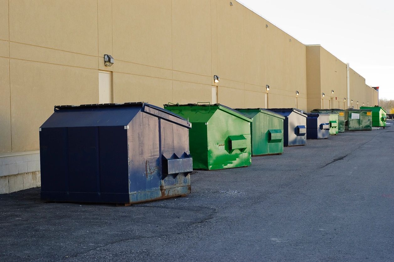 A row of dumpster bins in front of a building.